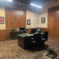 Senior government officer cabin with wood-panelled walls, executive desk and framed portraits at Stage 04