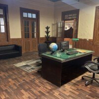 Side view of senior officer cabin with an executive desk, leather chair, windows and sofa seating