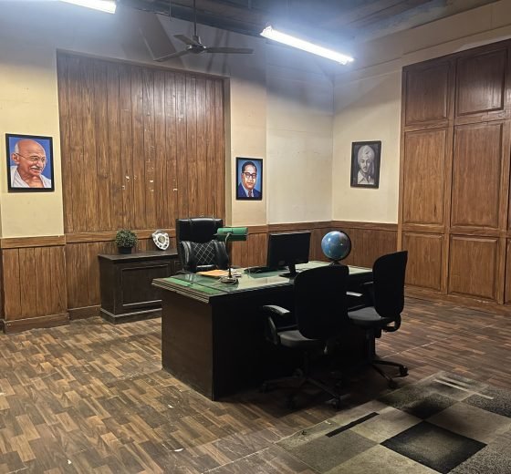 Senior government officer cabin with wood-panelled walls, executive desk and framed portraits at Stage 04